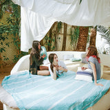 drei Mädchen chillen auf einem Sofa im Freien, das mit einem aquablauen Saunatuch bedeckt ist