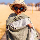 Kleines Kind in grauem Saunatuch Fouta am Strand