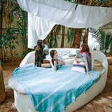 eine Gruppe von Mädchen die auf einem Bett mit einem aquablauen XXL Strandtuch im Freien faulenzen