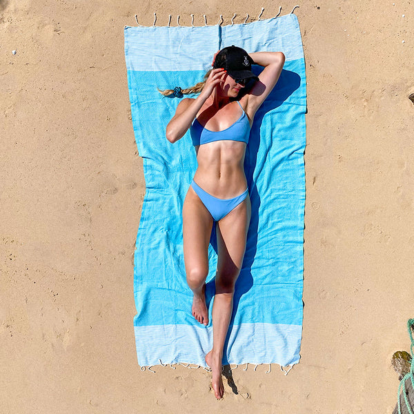 Mädchen im Bikini am Strand sonnt sich auf blauem Hamamtuch