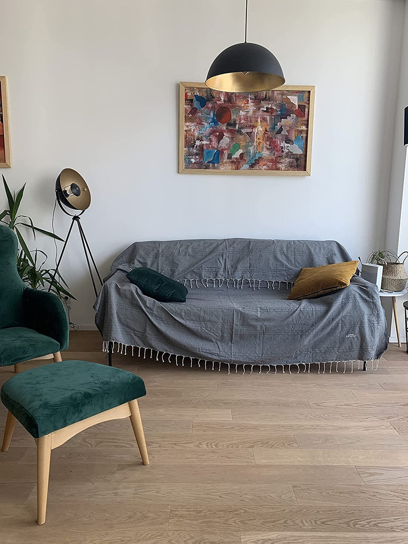ein Sofa mit dunkelgrauen Sofaüberwürf und Kissen im Wohnzimmer