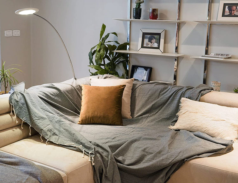eine dunkelgraue Sofaüberwurf Decke auf einem weißen Sofa mit Kissen