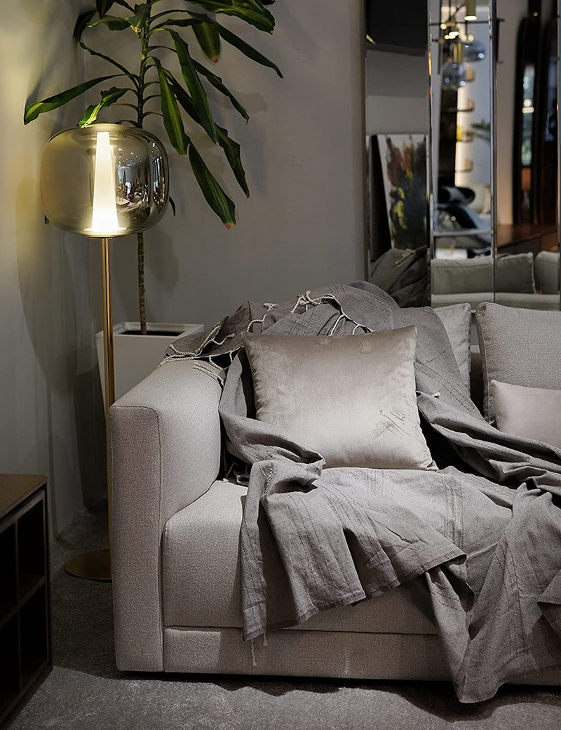ein graues Sofaüberwurf mit Kissen auf einer grauen Couch in einem grauen Themenzimmer