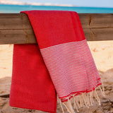 lachsrotes Strandtuch auf einem Stück Holz am Strand ausgelegt