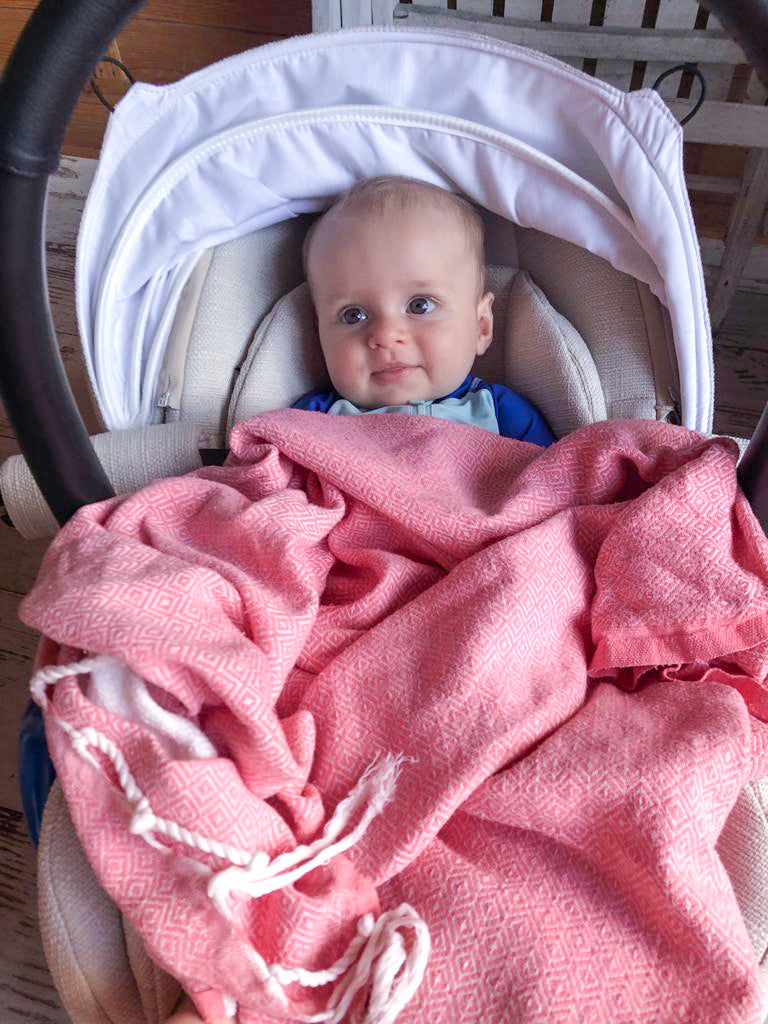 ein Baby in rosa Hamamtuch Fouta bedeckt