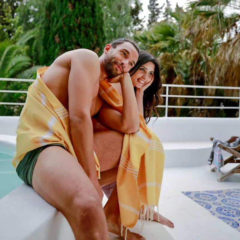 Paar in einer gelben Fouta am Pool