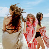 Mädchen chillen am Strand in rosa, korallenrosa und hellbraun fouta Strandtuch
