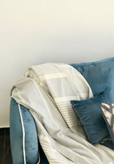 eine pastellgraue Sofaüberwurf auf einer blauen Samtcouch