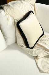 ein schwarz-weißes Kissen auf einer cremefarbenen Decke auf der Couch
